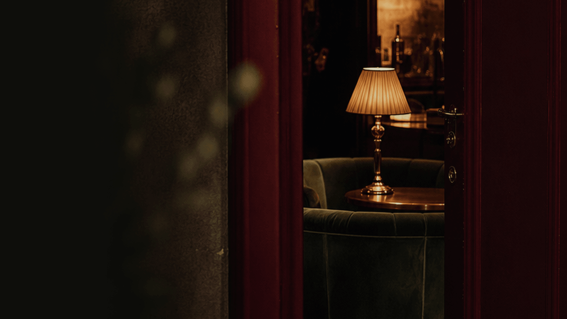 A velvet door, half-open, looking into a small booth lit by a single lamp