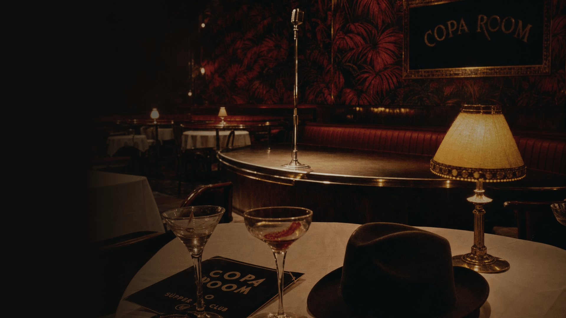 A table at the Copa Room, 1945 — coupe glasses, a man's hat, the stage and ribbon microphone behind